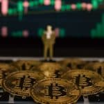 Bitcoins sobre computador com gráfico ao fundo