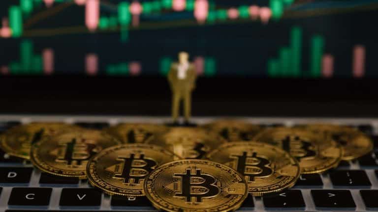 Bitcoins sobre computador com gráfico ao fundo