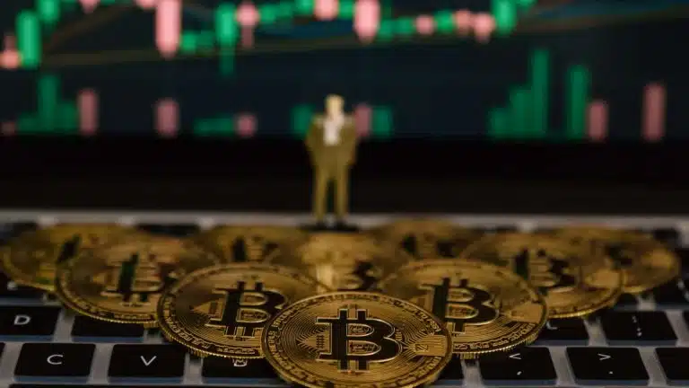 Bitcoins sobre computador com gráfico ao fundo