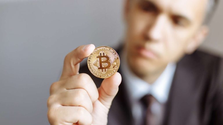 Homem desfocado olhando bitcoin Regras mais duras para criptoativos