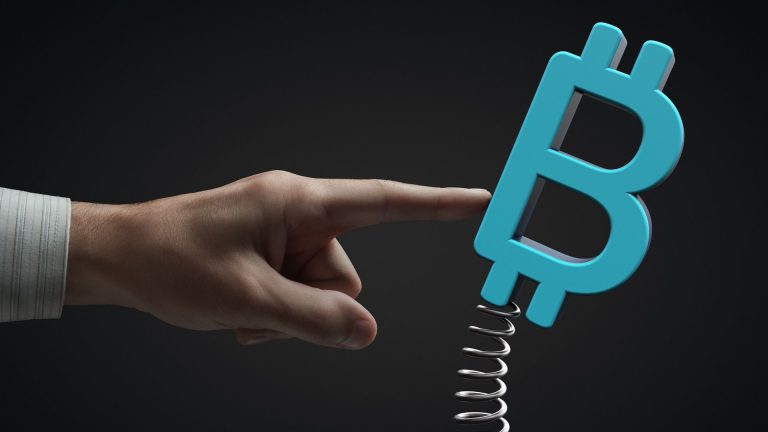 Mão empurrando bitcoin sobre uma mola, volatilidade