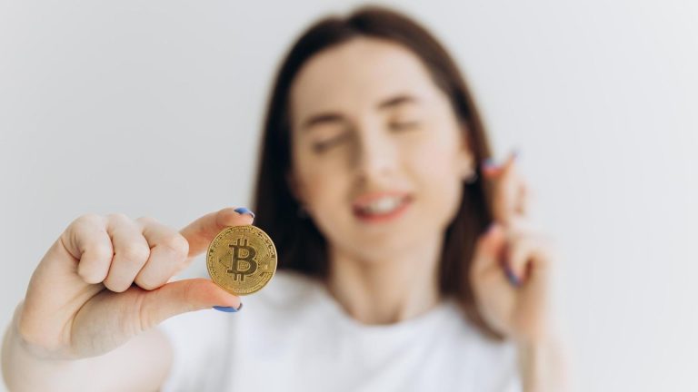 Mulher segurando bitcoin e torcendo ao fundo Binance vai dar bitcoin de graça para clientes que completarem quiz