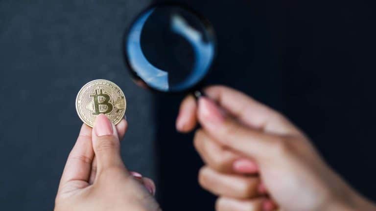 Pessoa segurando bitcoin e lupa em mãos FUNSEP contrata curso de Rastreio e Investigação de Bitcoin para 30 policiais civis do Amapá