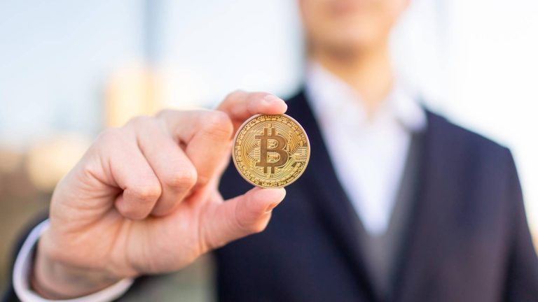 Pessoa de terno segurando bitcoin