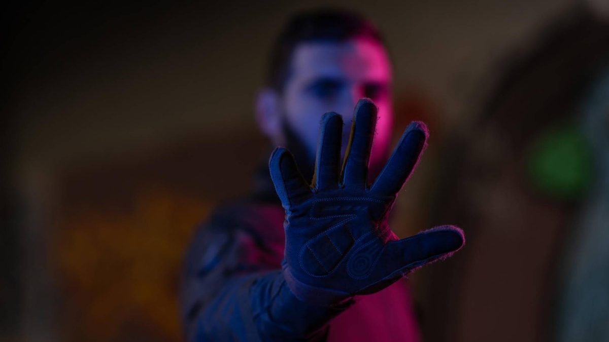 Homem com mão em frente ao rosto com fundo roxo