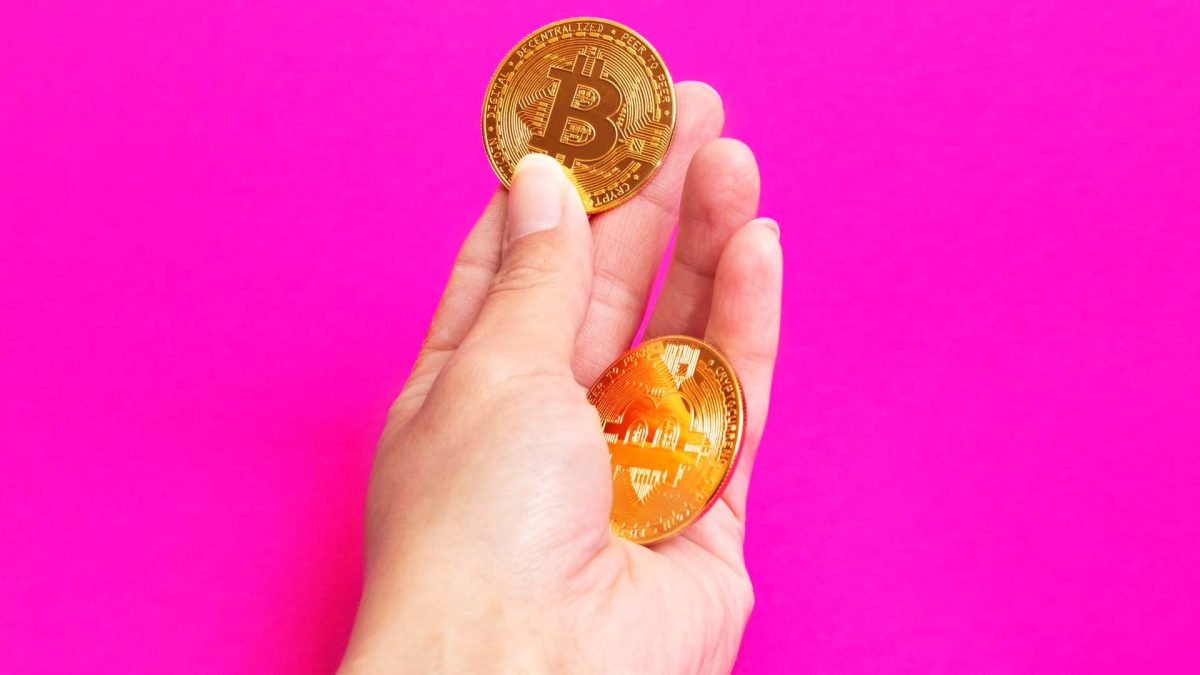 Bitcoin na mão com fundo rosa