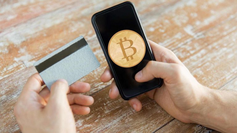 Cartão próximo de celular com símbolo do bitcoin