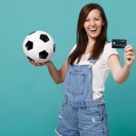 Mulher com cartão na mão e bola na outra Brasileiros gastaram mais de US$ 2,4 milhões nos países-sede da Copa do Mundo durante o mês com o Cartão OKX