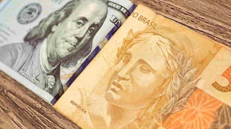 Nota de Dólar ao lado de divisa do Real brasileiro