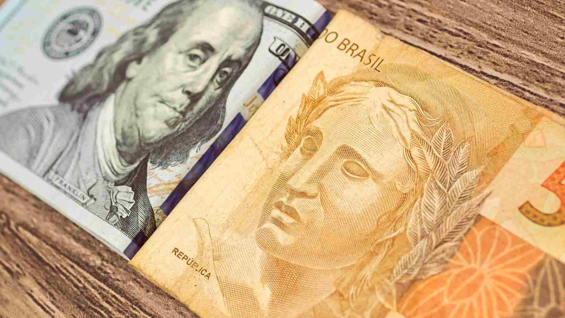 Nota de Dólar ao lado de divisa do Real brasileiro