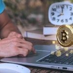 Bitcoin em destaque ao lado de computador e relógio Mercado Bitcoin cobra taxa de inatividade dos usuários que mantém menos de R$ 50 na corretora