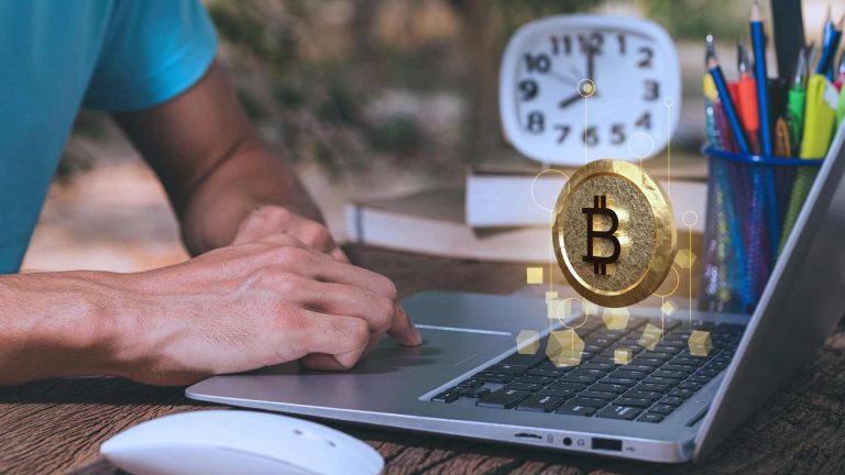 Bitcoin em destaque ao lado de computador e relógio Mercado Bitcoin cobra taxa de inatividade dos usuários que mantém menos de R$ 50 na corretora