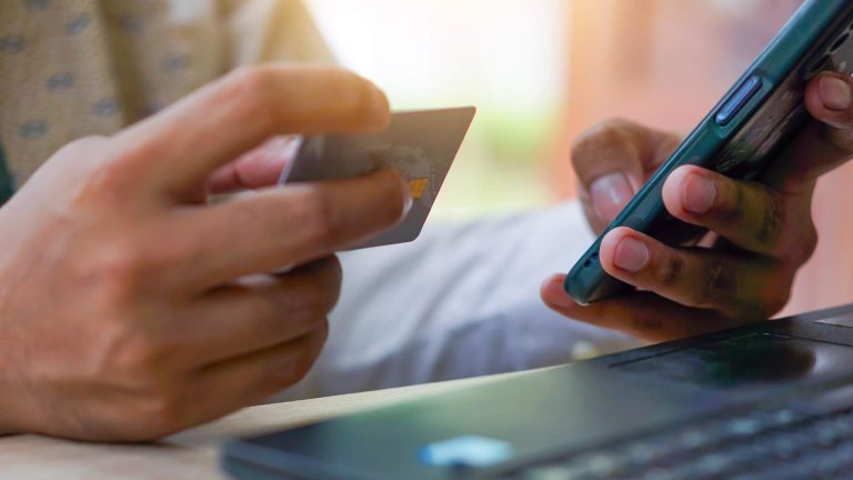 Celular e cartão de crédito na mão de pessoa