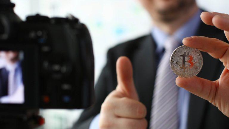Homem segurando bitcoin em live BTG Pactual, Itaú e Bradesco se unem a Banco Central para discutir regulação em evento da ANBIMA