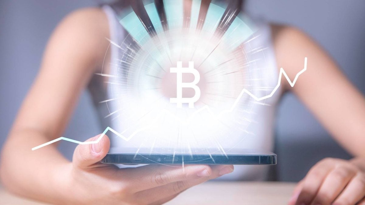 Mulher com símbolo do bitcoin brilhando em celular Mais um ataque hacker a empresa de bitcoin, agora no BTCPay Server, que pede atualização urgente a usuários