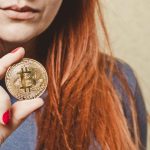 Mulher segurando bitcoin em destaque