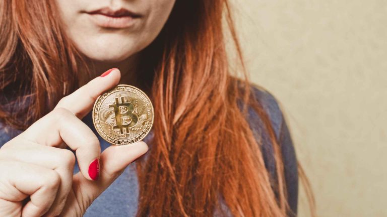 Mulher segurando bitcoin em destaque