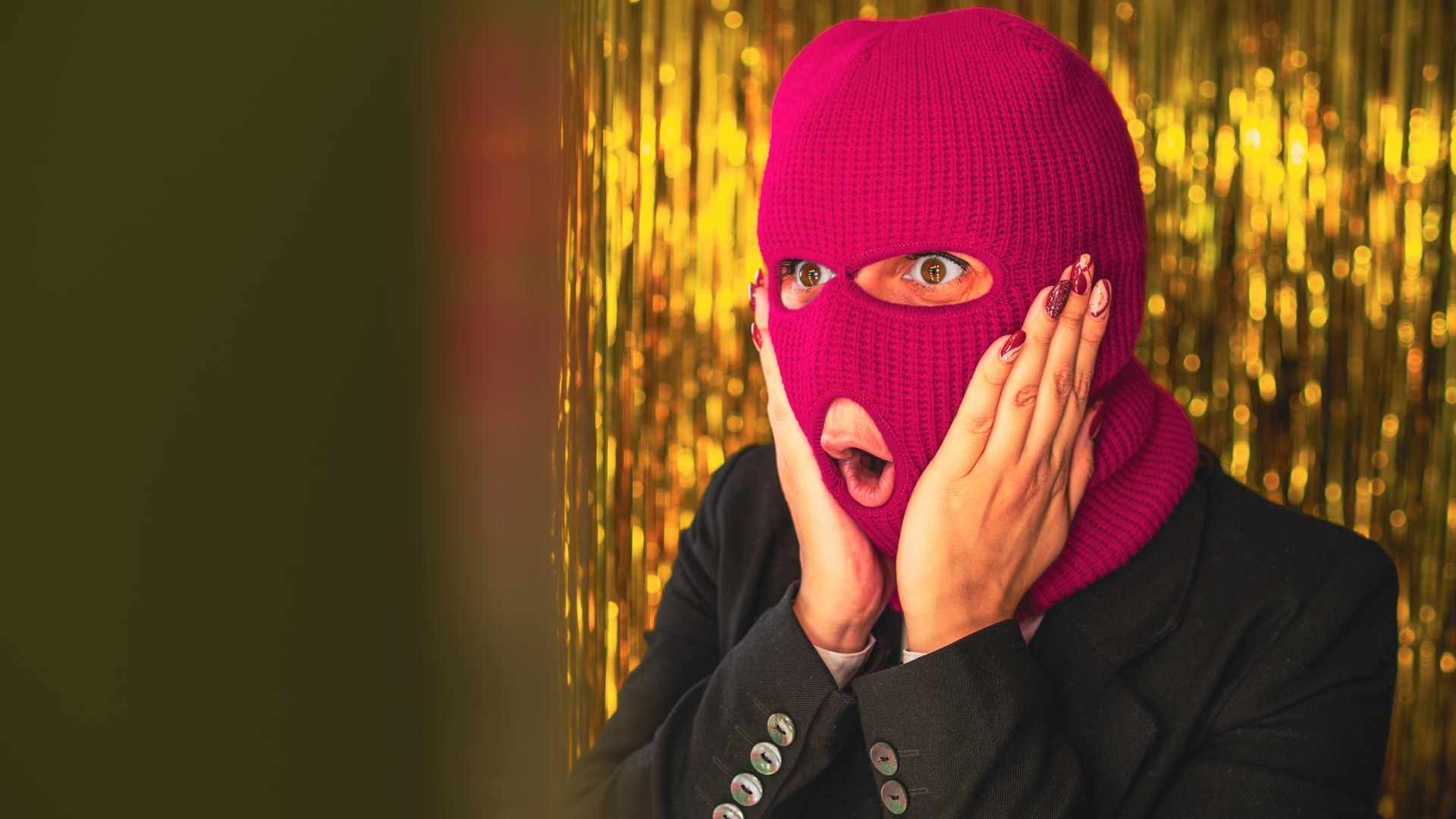 Mulher usando balaclava rosa Mulher é condenada a prisão por não declarar imposto de ganhos com criptomoedas obtidas por meio de roubo