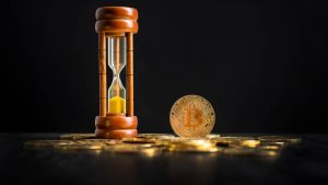 Bitcoin ao lado de ampulheta de tempo