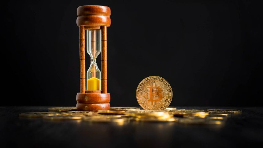 Bitcoin ao lado de ampulheta de tempo