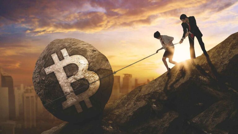 Homem e mulher tentando segurar pedra de bitcoin em montanha Ripio, Mercado Bitcoin e outras corretoras pedem registro no Banco Central antes do prazo final no dia 30 de outubro