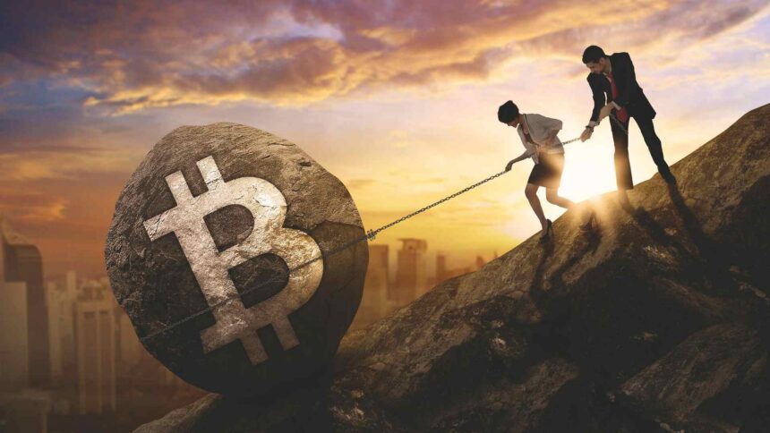 Homem e mulher tentando segurar pedra de bitcoin em montanha Ripio, Mercado Bitcoin e outras corretoras pedem registro no Banco Central antes do prazo final no dia 30 de outubro