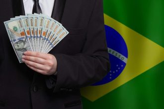 Homem segurando Dólar com bandeira do Brasil ao fundo
