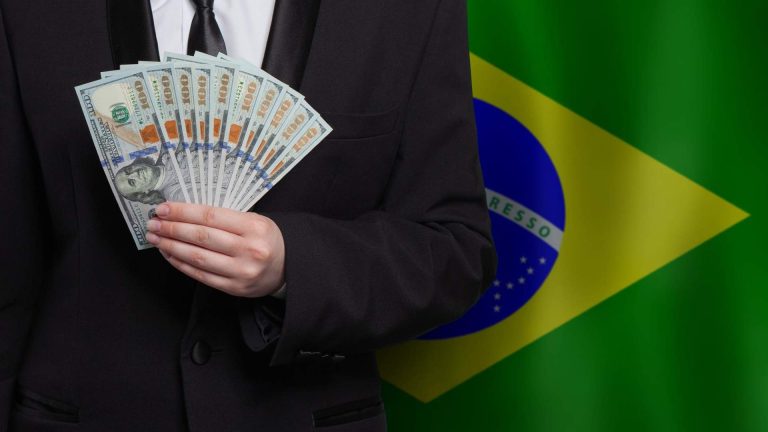 Homem segurando Dólar com bandeira do Brasil ao fundo