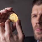 Homem segurando bitcoin com análise Prazo do Banco Central para corretoras de criptomoedas vence na sexta-feira (30), mas dia 6 de novembro preocupa especialista
