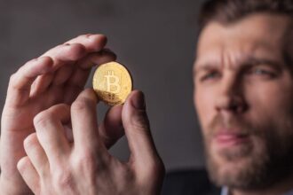 Homem segurando bitcoin com análise Prazo do Banco Central para corretoras de criptomoedas vence na sexta-feira (30), mas dia 6 de novembro preocupa especialista