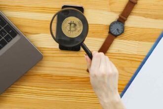 Lupa sobre bitcoin em mesa Banco Central publica regra que limita propagandas e ofertas de criptomoedas aos clientes