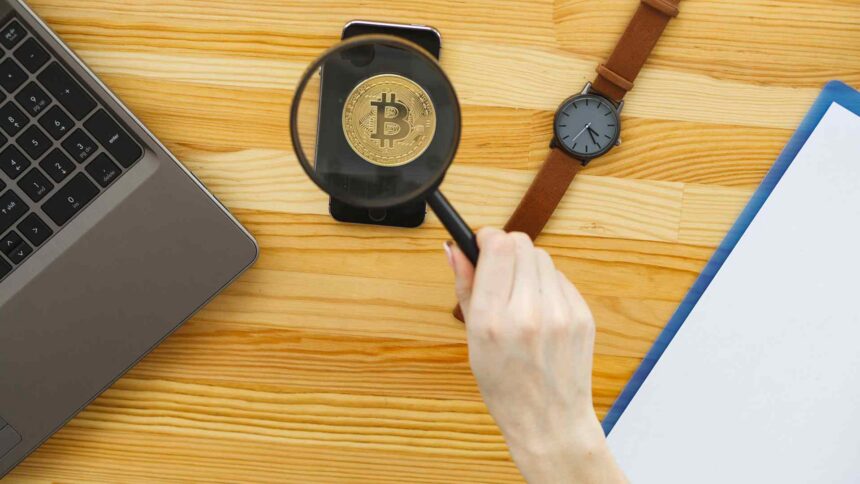 Lupa sobre bitcoin em mesa Banco Central publica regra que limita propagandas e ofertas de criptomoedas aos clientes