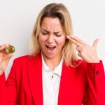 Mulher com bitcoin simbólico na mão e desesperada Contadora é acusada de inventar prejuízos com criptomoedas para fraudar imposto de renda nos EUA